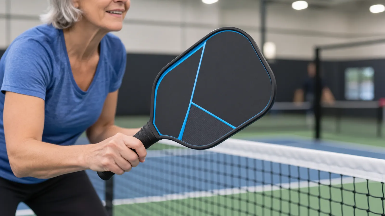 Close view of a woman's hands on a pickleball paddle grip at the kitchen line